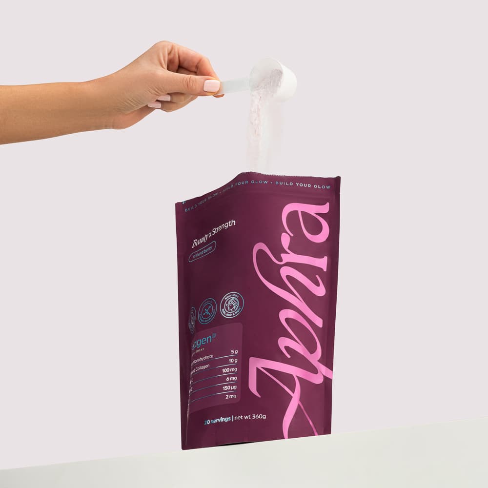 A hand holding a scoop above an Aphra product pouch